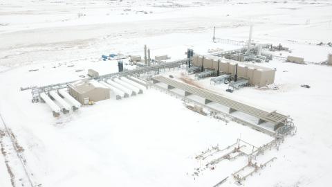 Aerial view of an industrial facility in snowy landscape, showcasing structures and machinery amidst expansive white surroundings.